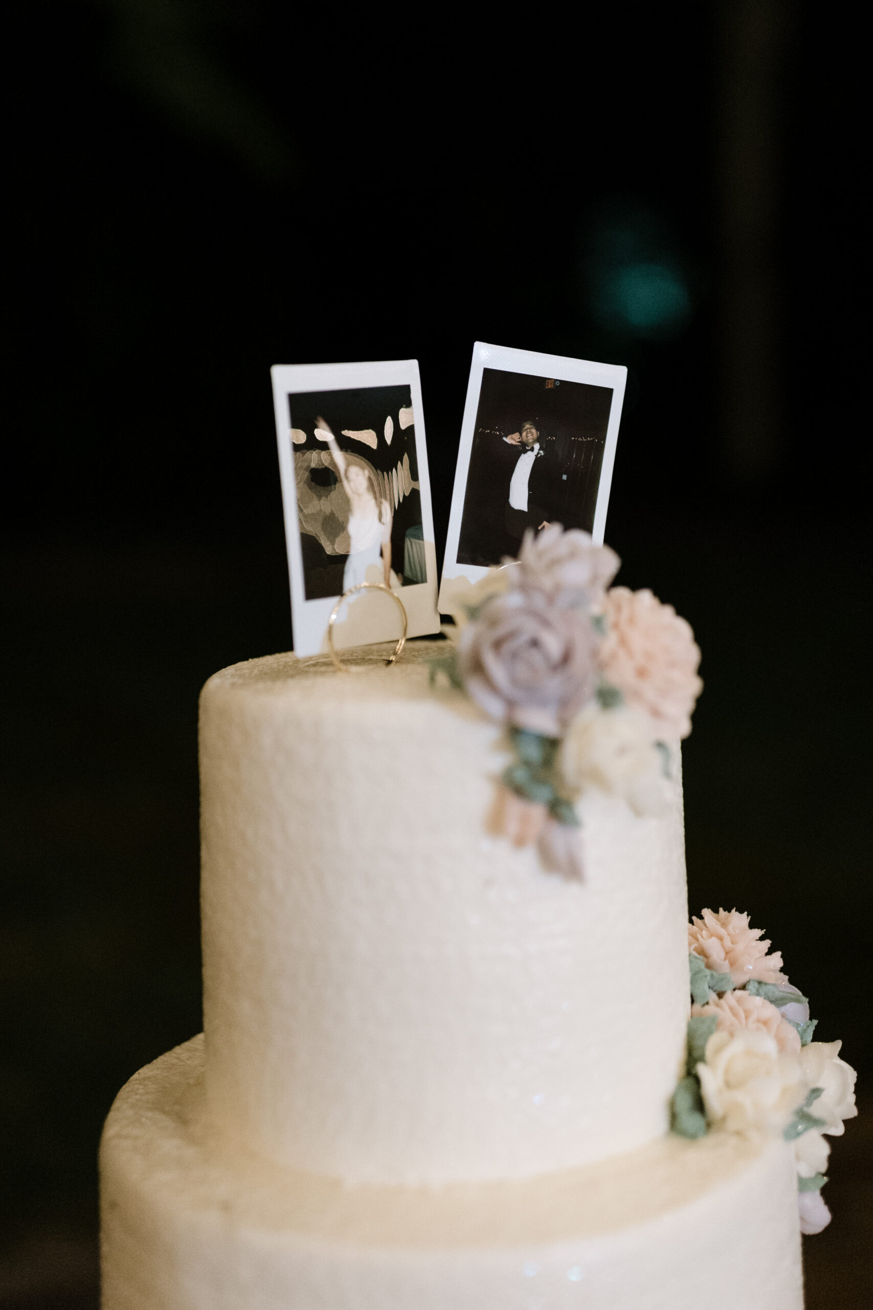 A Polaroid of a bride and groom sits on theop of a three-tier wedding cake