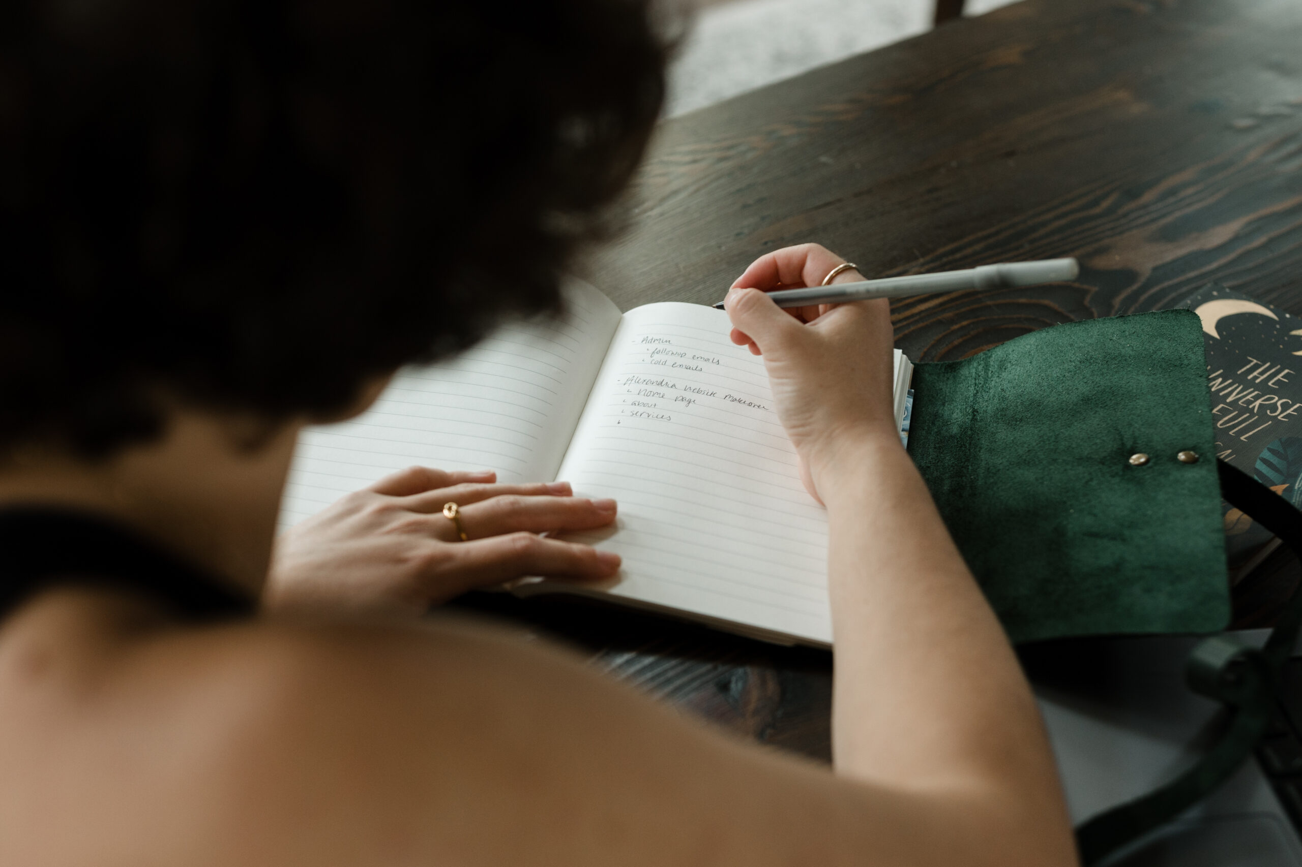 A wedding copywriter writes in a green leather journal