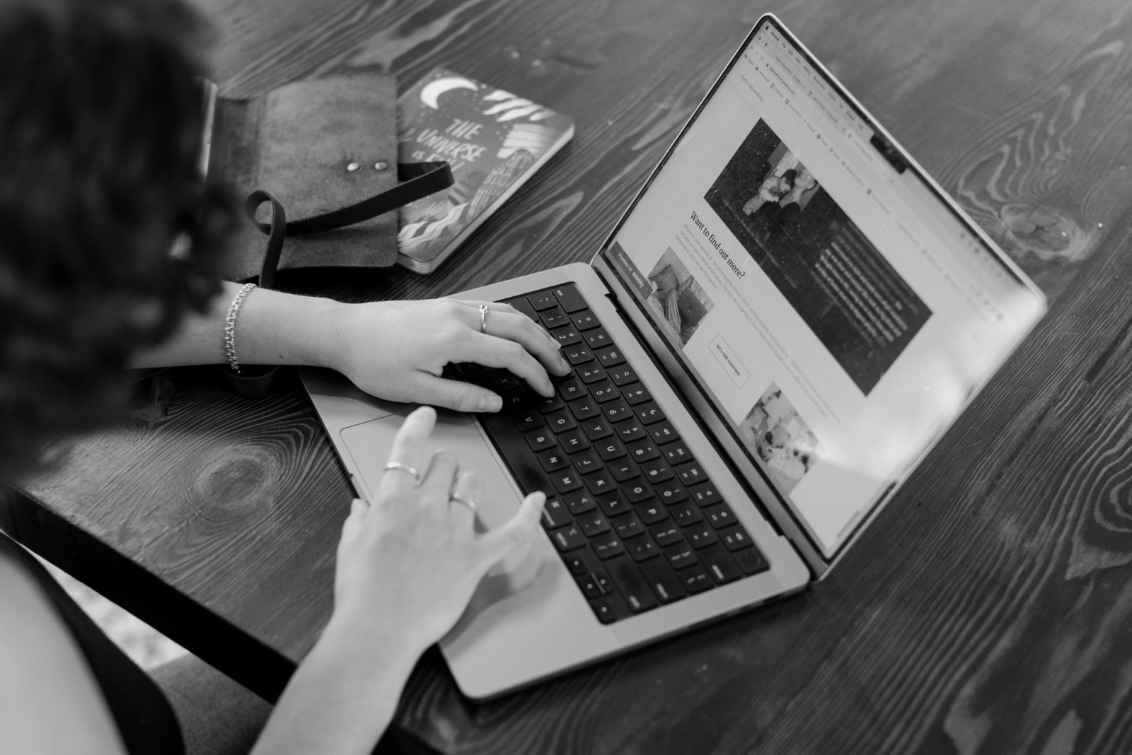 A black and white photo of a website copywriter typing on a laptop computer
